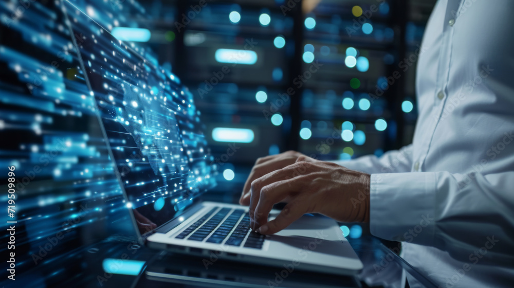 Poster person's hands typing on a laptop with digital data streaming from the screen into a server room