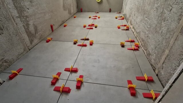 laying tiles in the toilet. Leveling and setting the tiles requires self-leveling wedges. plastic aids in each corner lift the tile into the washed position and height. preventing entry from brooms