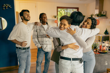 Group of young friends happy to meet and embracing each other at festive home party