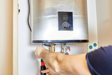 the man tightens the pipe nut in the water heating system. The master installs the water heater....