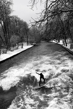 a surfer in the eisbach river in germany in winter perpendicular
