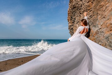 Woman beach white dress flying on Wind. Summer Vacation. A happy woman takes vacation photos to send to friends.