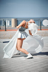 Young sexy girl in space silver micro skirt dancing with white silk scarf waving gracefully, female...