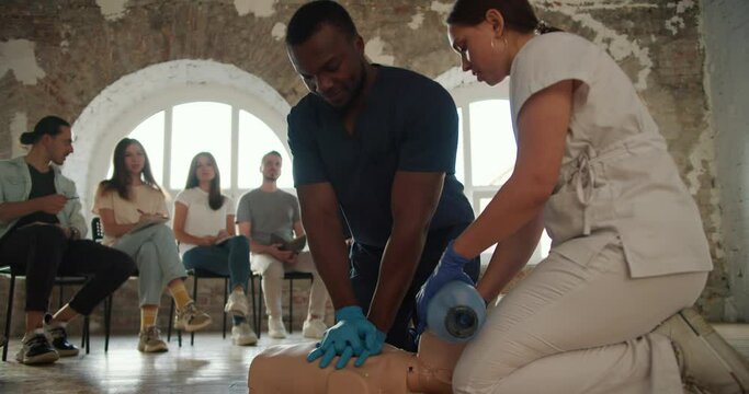 Close-up shooting: a female doctor in a white uniform conducts a medical first aid course for the public, who listens by showing artificial respiration on the mannequin using the Ambu resuscitation