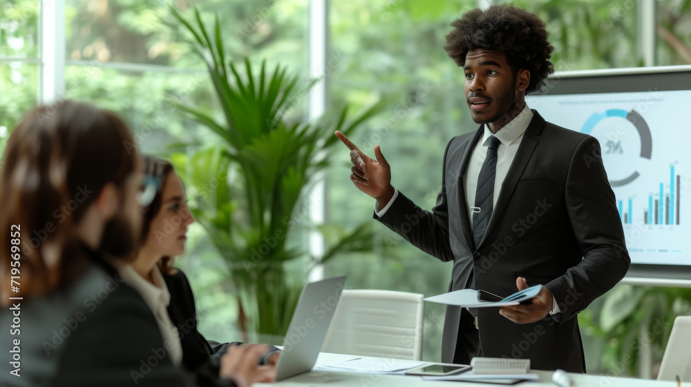Poster business presentation taking place with a well-dressed man pointing at a chart on a display board wh