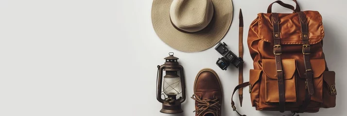 Poster Vintage adventurer essential gear flat lay. Hat, backpack, film camera, gas lamp and boots on white background isolated. Minimal style hiking concept. Wanderlust vibes. © Zahid