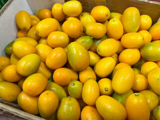 Kumquat in a box at the supermarket. Slightly green fruit. A large amount of vitamins