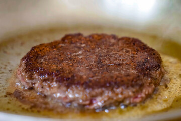 Cooking burger beef patty on a hot frying plate close up. Preparing burger, homemade. Grocery product advertising, menu.