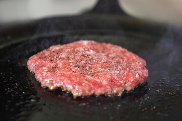 Cooking burger beef patty on a hot frying pan close up. Preparing burger, homemade. Grocery product advertising, menu.