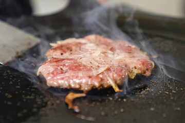 Cooking burger beef patty on a hot frying pan close up. Preparing burger, homemade. Grocery product advertising, menu.