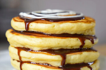 Pancakes fluffy stack with chocolate on white plate, delicious food. Homemade freshly baked pancakes for American breakfast, menu, advert or package, close up.