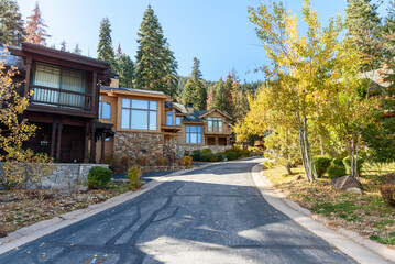 Modern houses along a street in a forested mountain setting on a sunny autumn day