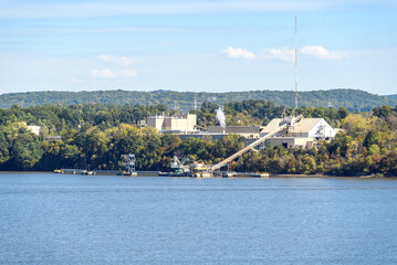 Manufacturing plant with private jetty on the forested bank of a river on a sunny autumn day