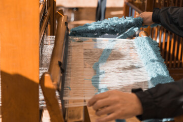 Fototapeta na wymiar Master weaver is weaving the tapestry with diverse bright threads, close up. Artisanal at work
