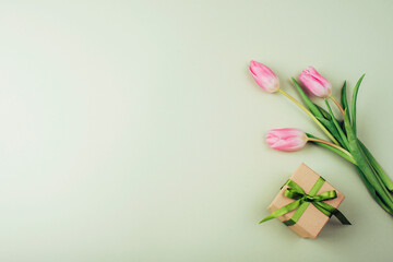 Gift box and bouquet of pink tulips on green background. Women's day, Mother's day, spring concept. Top view, flat lay, copy space