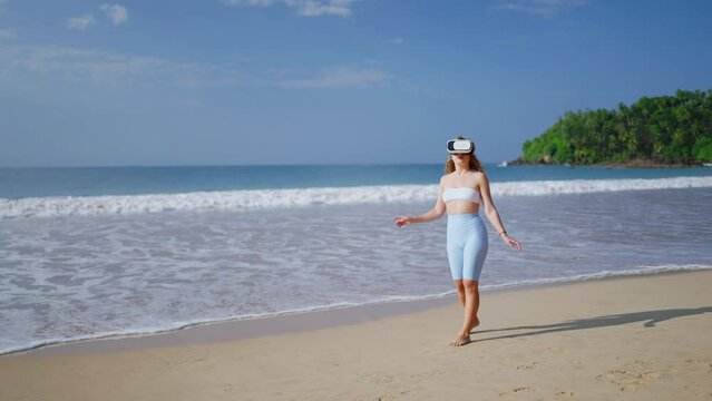 Woman explores virtual world, wearing VR headset on sunny beach, experiences immersive tropical environment, interacts with digital elements unseen to viewer, conveys modern leisure activity. Slowmo