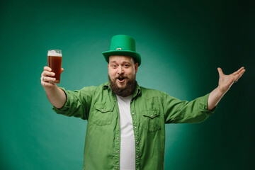 Happy bearded man with a glass of beer on a dark green background. Saint Patrick's Day Celebration