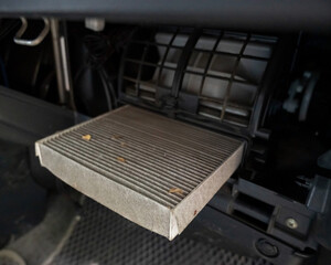 A mechanic changes the cabin air filter of a car. Dirty car cabin air filter. Timely car service. 