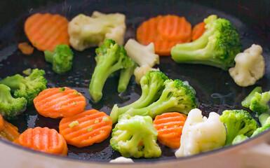 Healthy fresh meal cooking, chopped broccoli, carrot on frying pan, food preparation. Homemade vegetables for menu, advert or package, close up, selective focus.