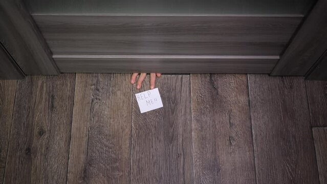 The girl pushes a note under the door that says &ldquo;help me". The girl&rsquo;s hand throws a sheet of paper with alarming text under the door. The person is in danger. The child anonymously asks for help.