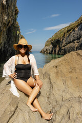 Beautiful young Latin woman, poses on a paradisiacal beach, wearing a white blouse and a straw hat