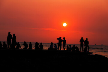 group of people gathering and relaxing in a beach at evening sunset