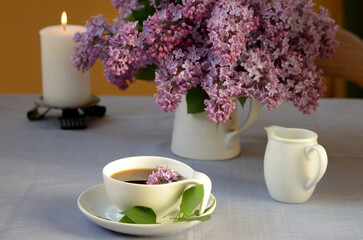 beautiful still life with purple flowers, a cup of tea and a candle