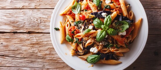 Pasta Alla Norma Delicious Sicilian pasta dish with roasted eggplant marinara tomato sauce grated ricotta and fresh basil served in a white ceramic bowl Wooden table selective focus vertical - obrazy, fototapety, plakaty