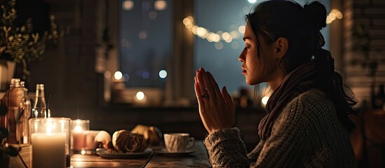 Young woman prays to God in the apartment at night close up. Copy space image. Place for adding text