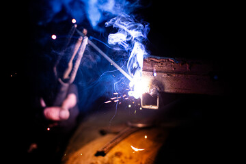 smoke and sparks close-up from electric arc welding in the dark
