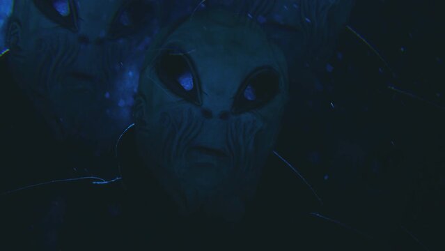 Kaleidoscope effect of grey alien standing outdoors under snowfall and looking at camera during the night, ufo light blinking in the background