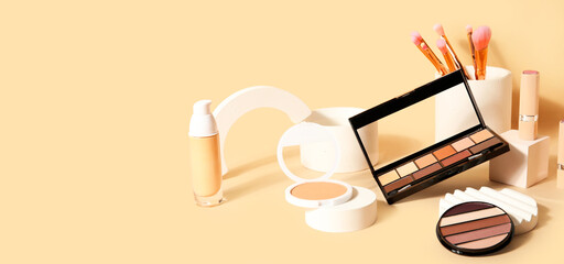 Decorative cosmetics, brushes and podiums on beige background with space for text