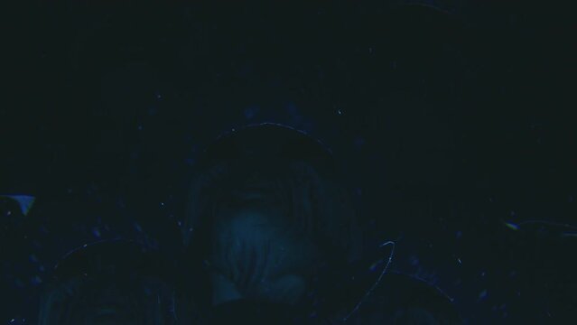 Kaleidoscope effect of alien looking up at the sky while standing outdoors under snowfall and strobe ufo light during night. Low angle shot