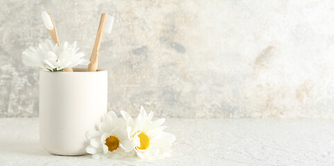 Holder with toothbrushes and chamomile flowers on grunge background. Banner for design