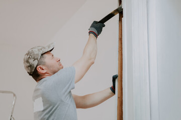 Hands of a man working with a crowbar indoors.