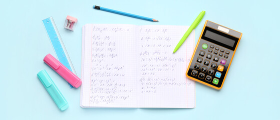 Copybook with maths formulas, calculator and stationery on light blue background