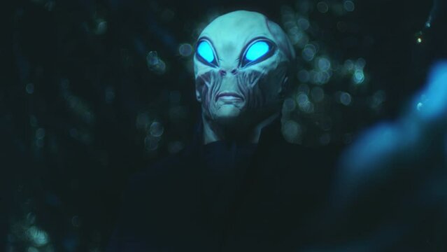 Extraterrestrial alien with glowing eyes standing outdoors at night and staring in the dark after arrival on Earth