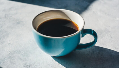 One cup of black coffee on a light background with a hard shadow.