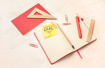 Sticky note with word GOAL and stationery on light background