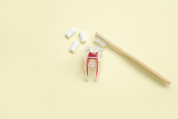 Plastic tooth with brush and chewing gums on light yellow background