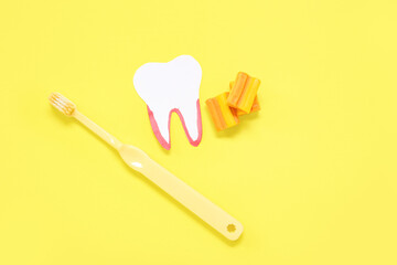 Paper tooth with brush and chewing gums on yellow background