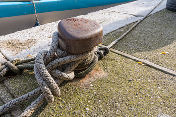 Fototapeta premium Close-up of a knot made with a fishing boat rope moored to an iron peg in a port in Grado, Italy. Articles for fishing boats. Marine items.