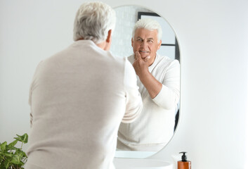 Fototapeta premium Senior man looking in mirror at home