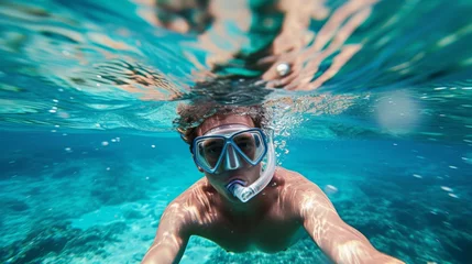 Fotobehang Young man snorkeling in clear tropical turqoise waters © Nikodem