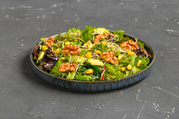 Plate with fresh salad on black background