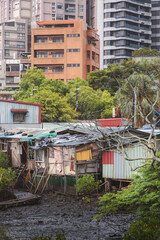 Example of gentrification with poor stilt house in mud contrasted against modern high rise buildings in Tamsui District, Taipei, Taiwan.