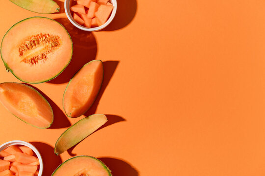 Sweet melons and bowls with pieces on orange background