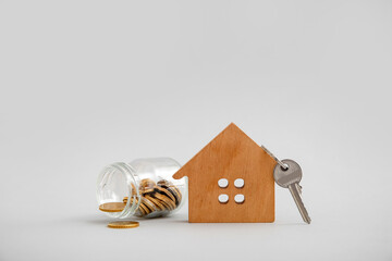 Wooden house figure with money and key on grey background. Concept of buying real estate