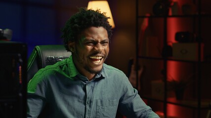 Obraz premium Smiling gamer feeling happy after receiving winner screen on rgb lit PC desktop for killing all enemies. Close up shot of delighted player bragging after being victorious in gaming computer videogame
