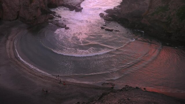 Aerial: Dreamy abstract waves crashing in concentric circle in slow motion at sunset giving the feeling of heaven
